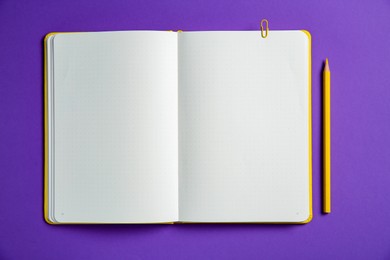 Photo of Blank notebook and pencil on purple background, top view. Space for text