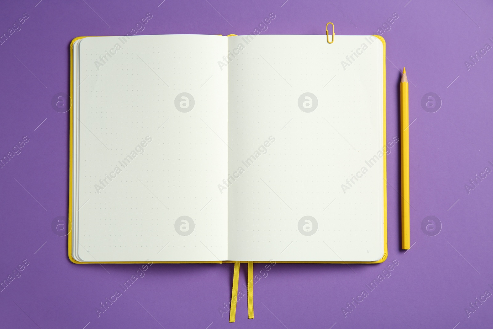 Photo of Blank notebook and pencil on purple background, top view. Space for text