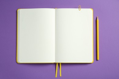 Photo of Blank notebook and pencil on purple background, top view. Space for text