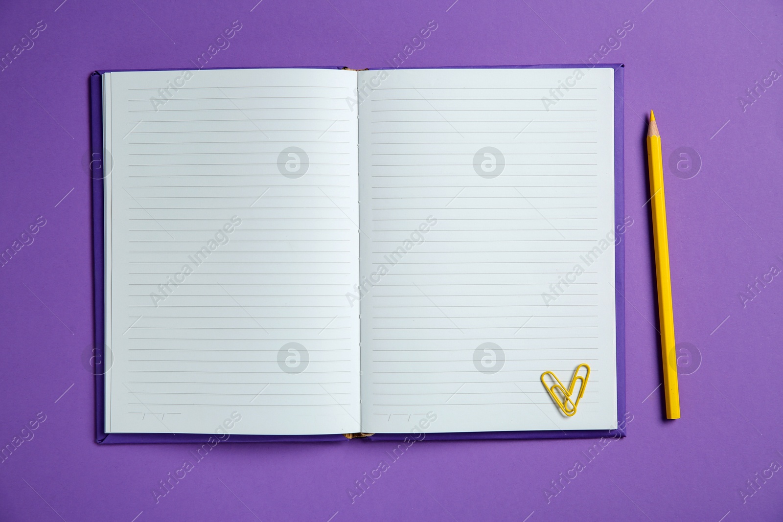 Photo of Blank notebook, paper clips and pencil on purple background, top view. Space for text