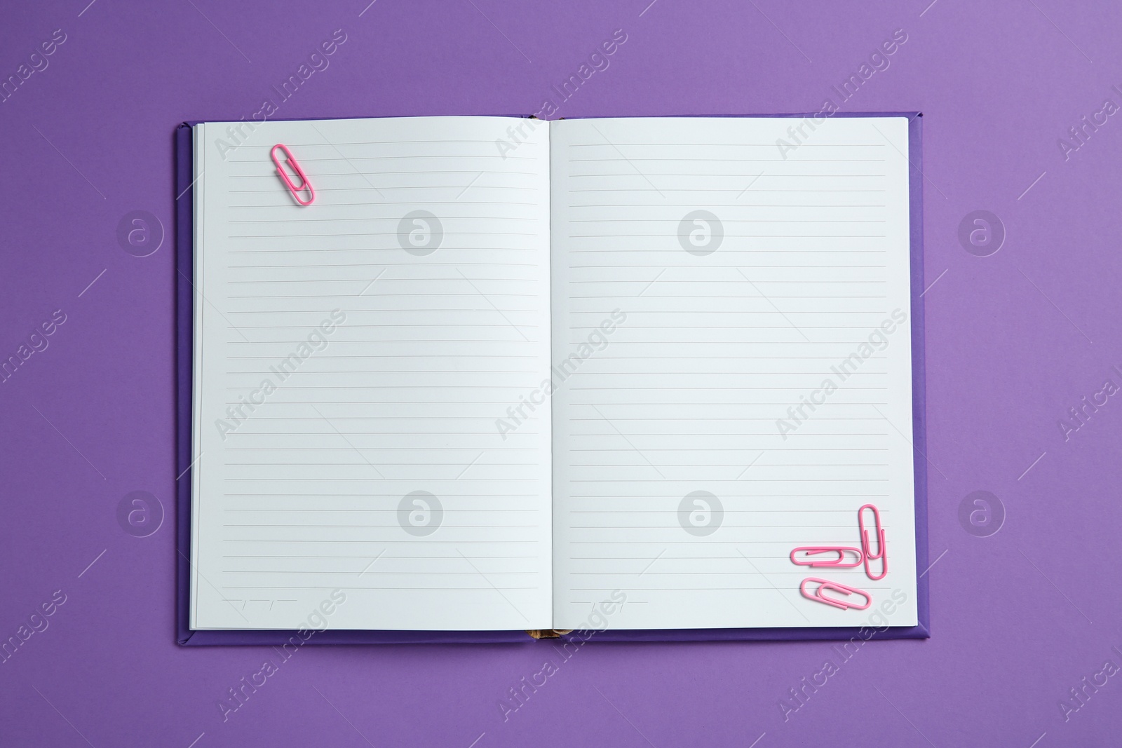 Photo of Blank notebook with paper clips on purple background, top view. Space for text