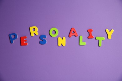 Photo of Word Personality made of colorful letters on purple background, top view