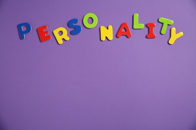 Photo of Word Personality made of colorful letters on purple background, top view. Space for text