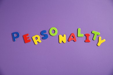 Photo of Word Personality made of colorful letters on purple background, top view