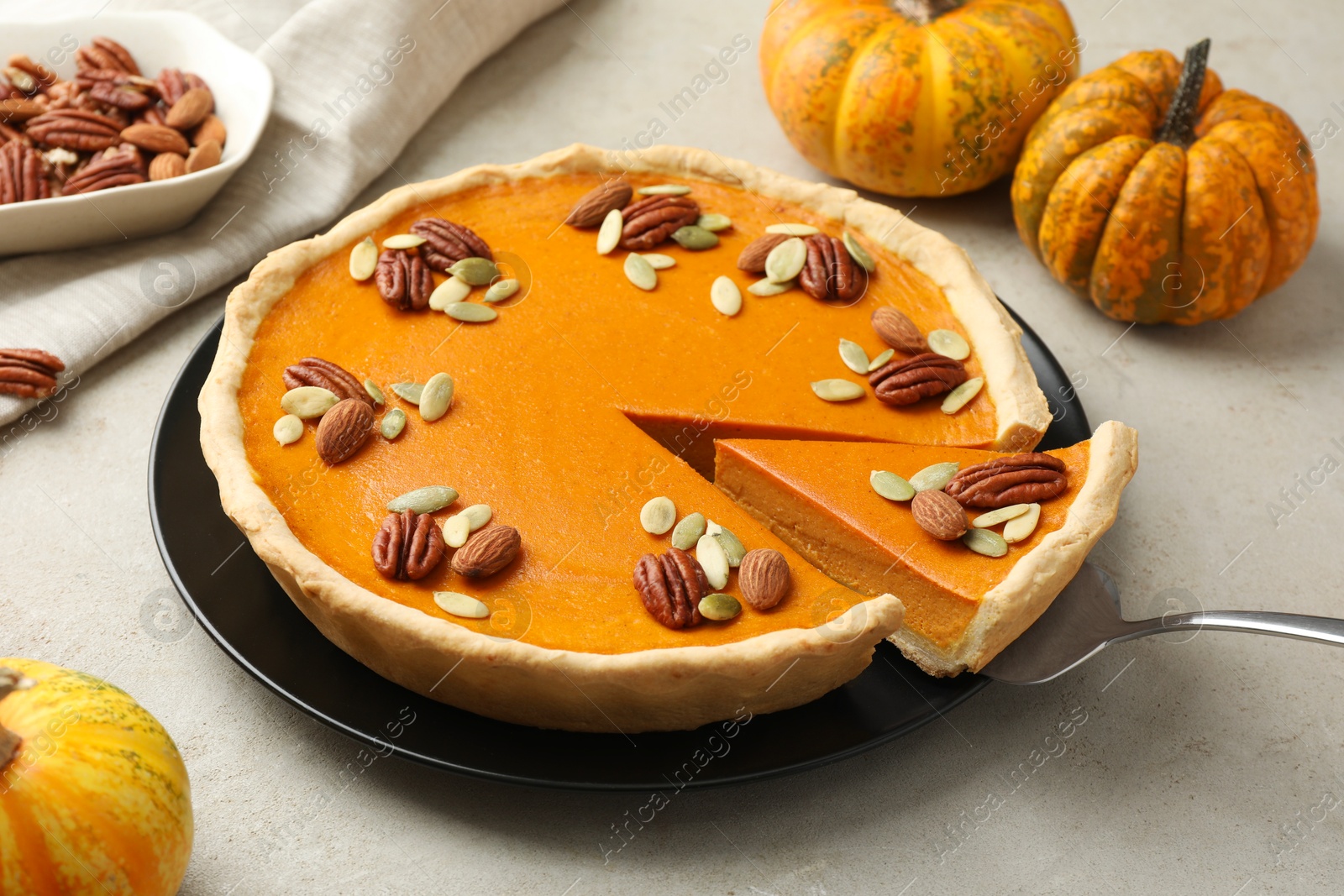 Photo of Taking piece of tasty homemade pumpkin pie at grey table, closeup