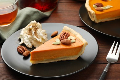 Photo of Piece of tasty homemade pumpkin pie served on wooden table, closeup