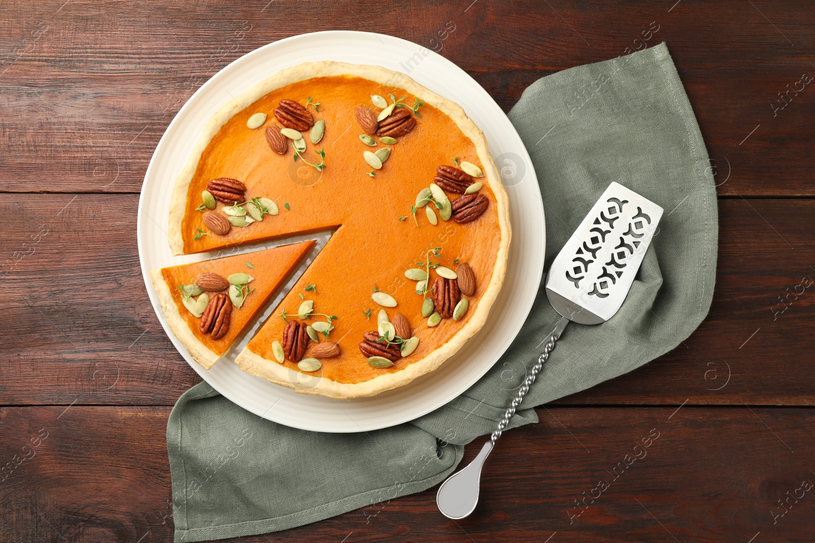 Photo of Tasty homemade pumpkin pie and server on wooden table, top view