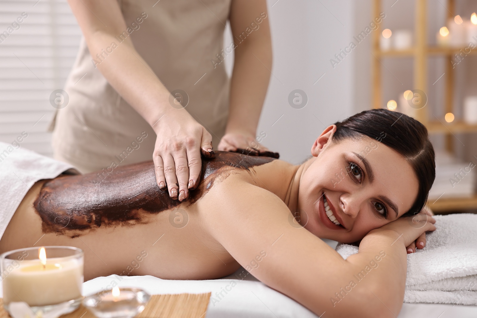 Photo of Woman undergoing chocolate body wrap treatment in spa salon