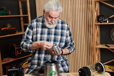 Relaxing hobby. Senior man repairing meat grinder in workshop