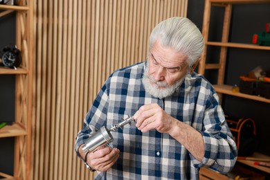 Photo of Relaxing hobby. Senior man repairing meat grinder in workshop