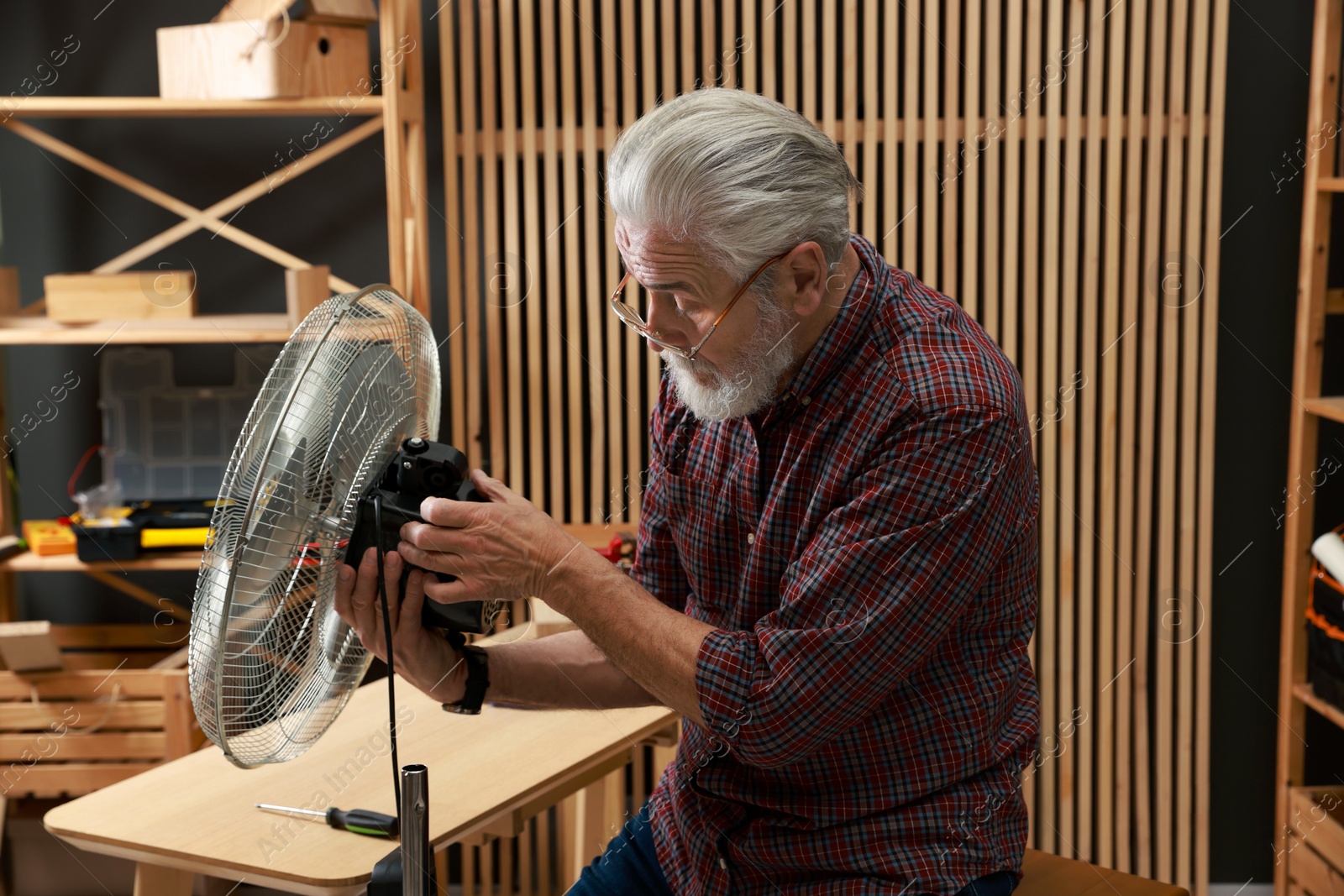 Photo of Relaxing hobby. Senior man repairing fan in workshop