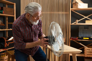 Photo of Relaxing hobby. Senior man repairing fan in workshop