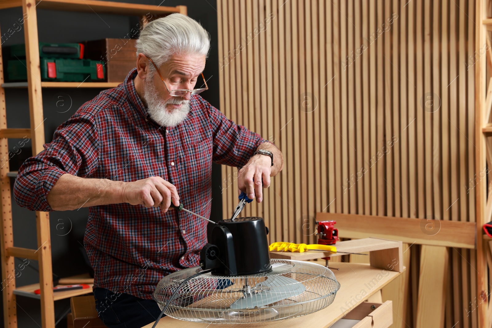 Photo of Relaxing hobby. Senior man repairing fan in workshop