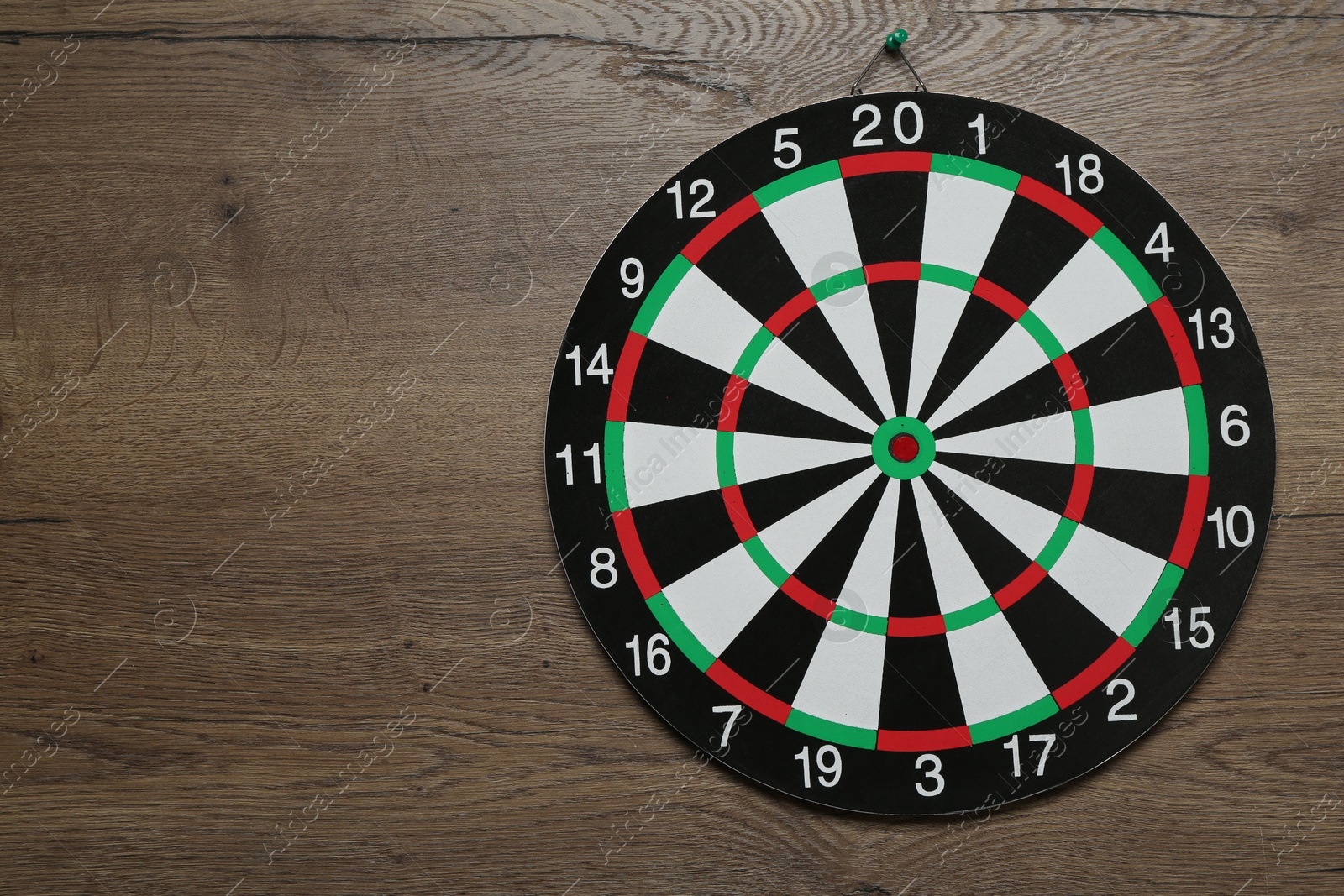 Photo of One dart board hanging on wooden background. Space for text