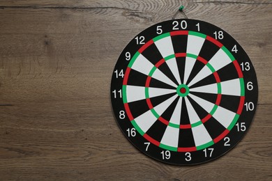 Photo of One dart board hanging on wooden background. Space for text