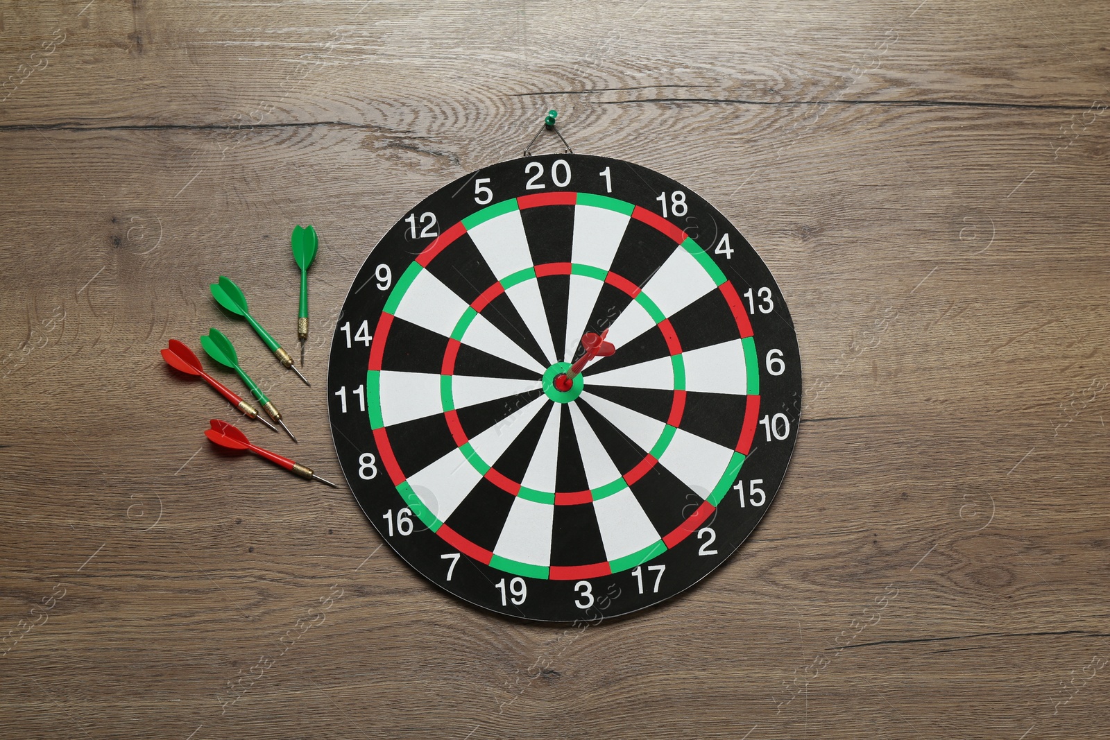 Photo of Dart board and colorful arrows on wooden background, flat lay