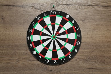 Photo of Dart board and red arrow on wooden background