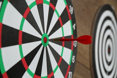 Photo of Dart boards and red arrow on wooden background, closeup