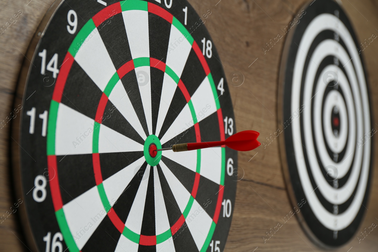 Photo of Dart boards and red arrow on wooden background, closeup