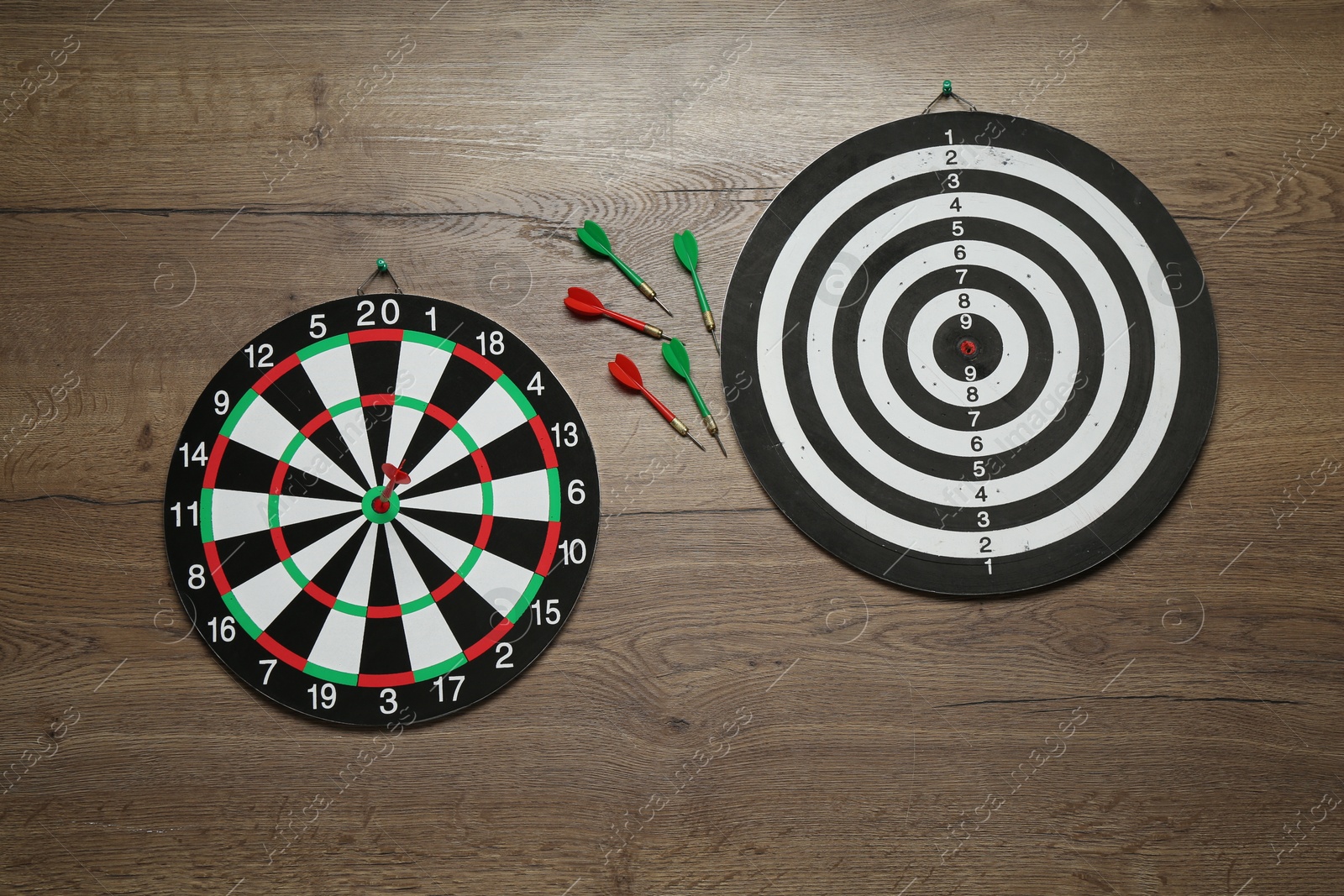 Photo of Dart boards and colorful arrows on wooden background, flat lay