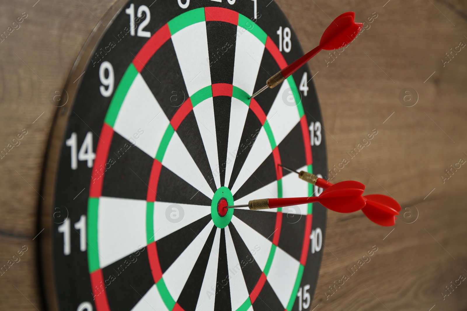 Photo of Dart board and red arrows on wooden background, closeup