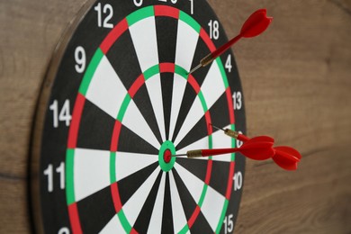 Photo of Dart board and red arrows on wooden background, closeup