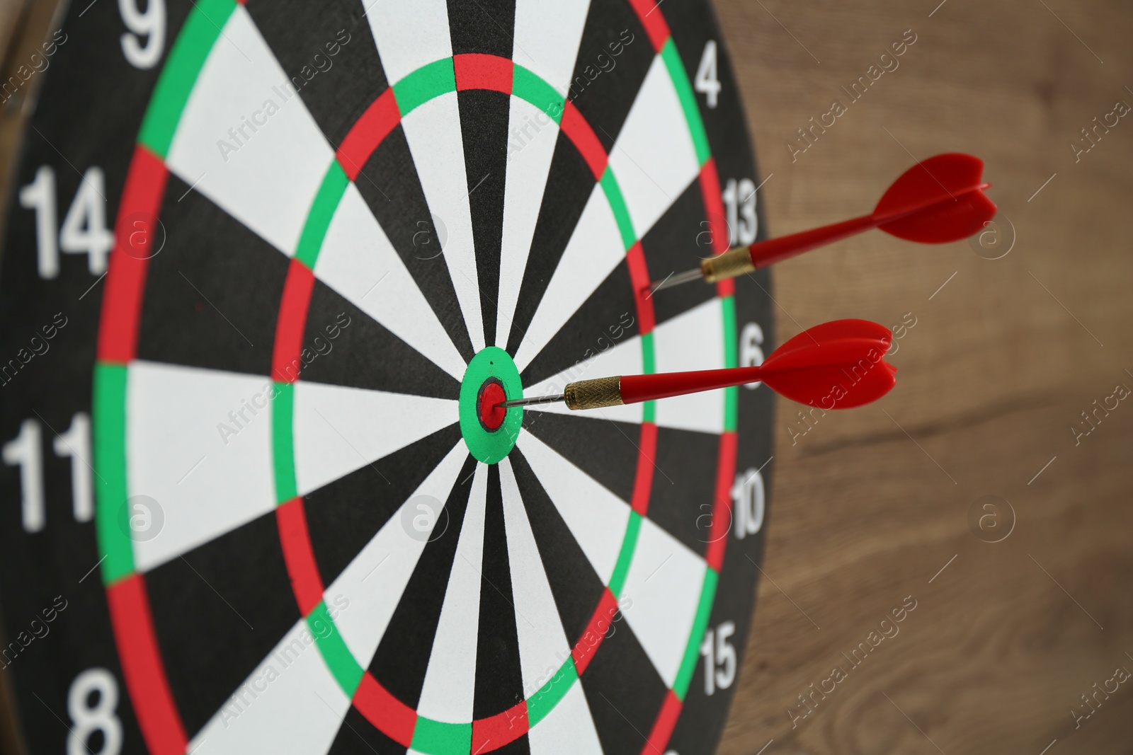 Photo of Dart board and red arrows on wooden background, closeup