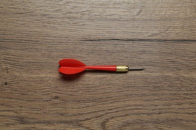 Photo of One red dart arrow on wooden table, top view