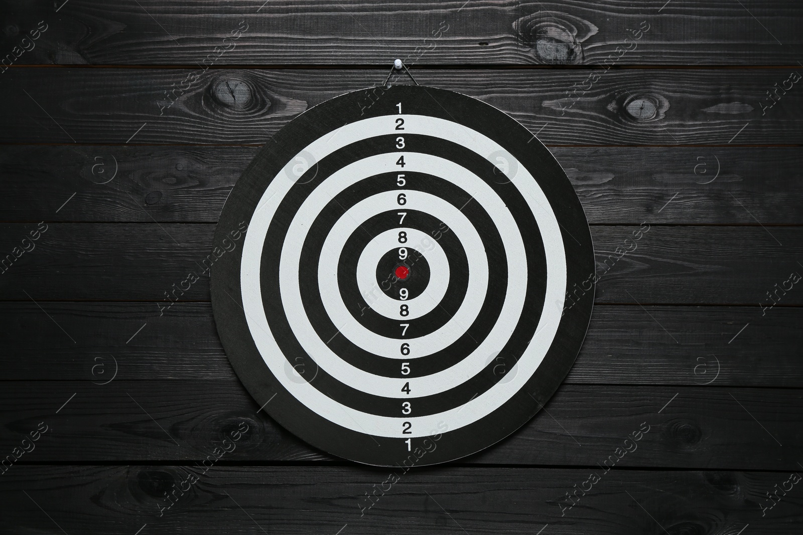 Photo of One dart board hanging on black wooden background