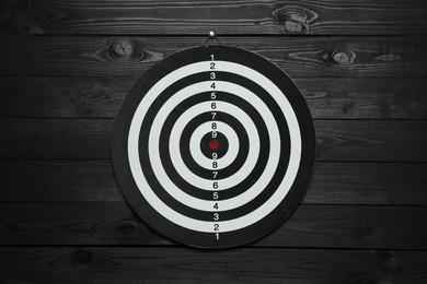 Photo of One dart board hanging on black wooden background