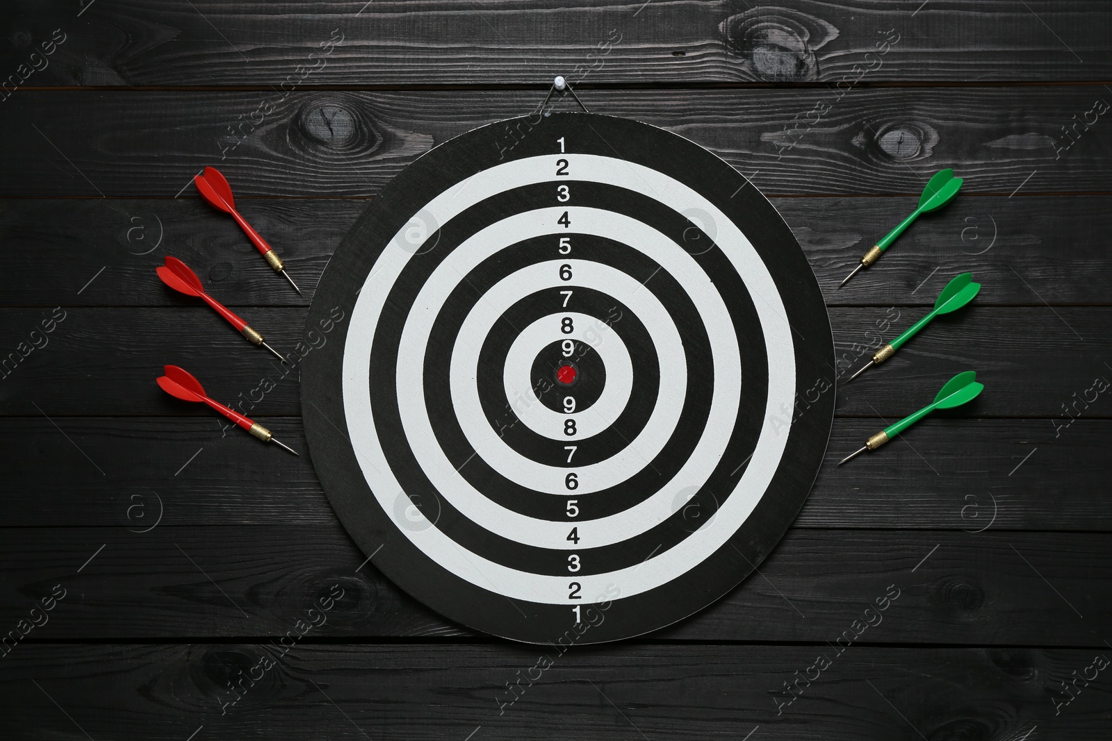 Photo of Dart board and colorful arrows on black wooden background, flat lay