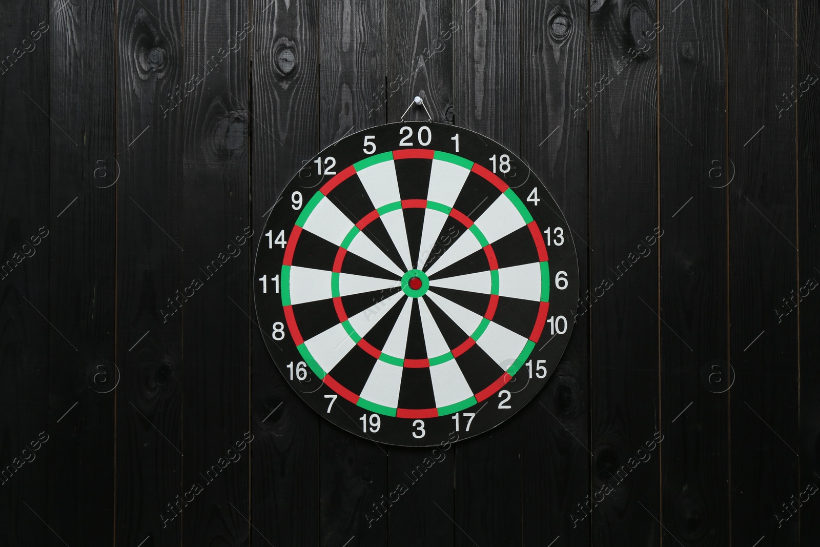 Photo of One dart board hanging on black wooden background