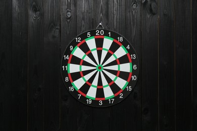 Photo of One dart board hanging on black wooden background