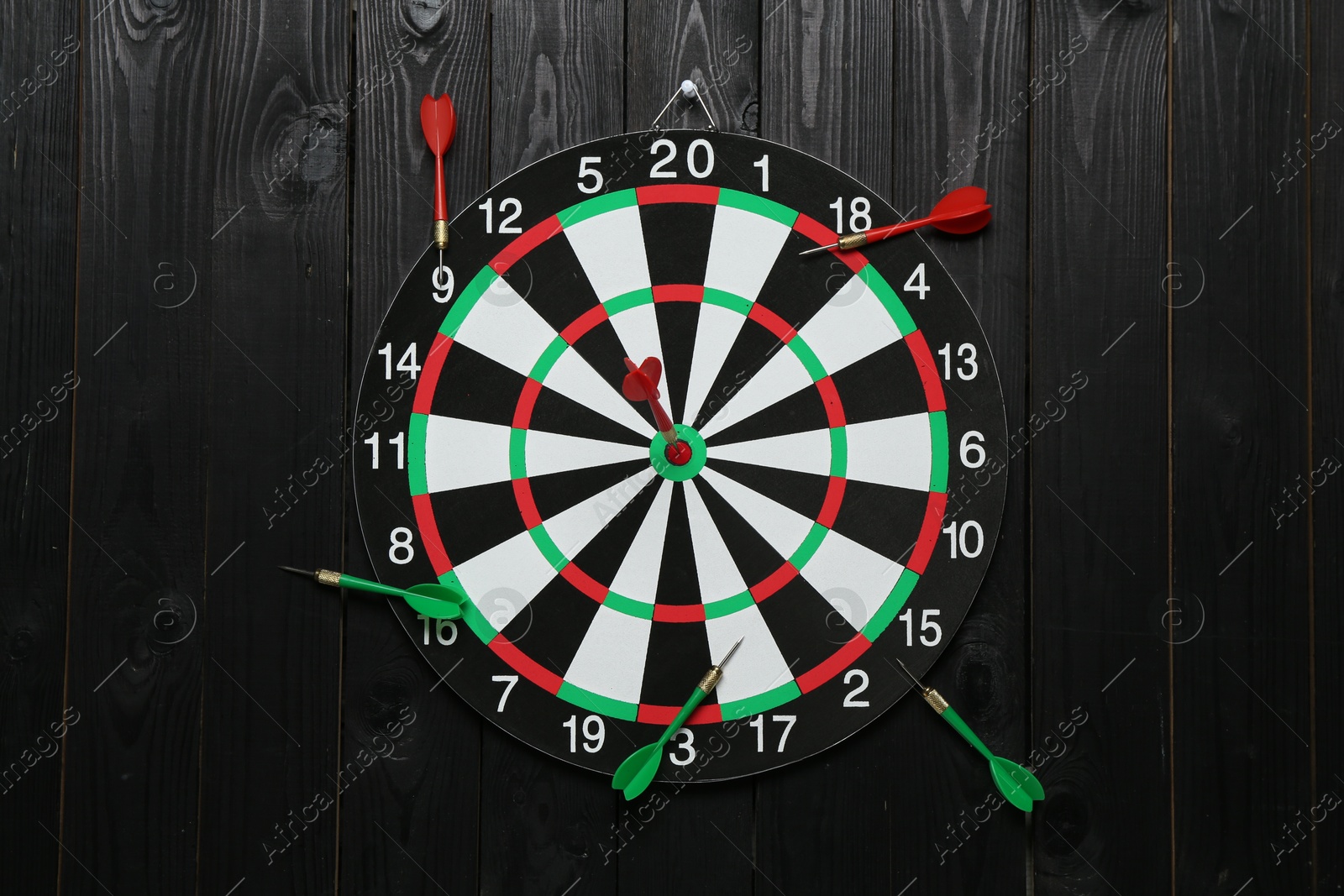 Photo of Dart board and colorful arrows on black wooden background, flat lay