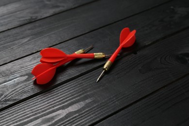 Photo of Red dart arrows on black wooden table, closeup