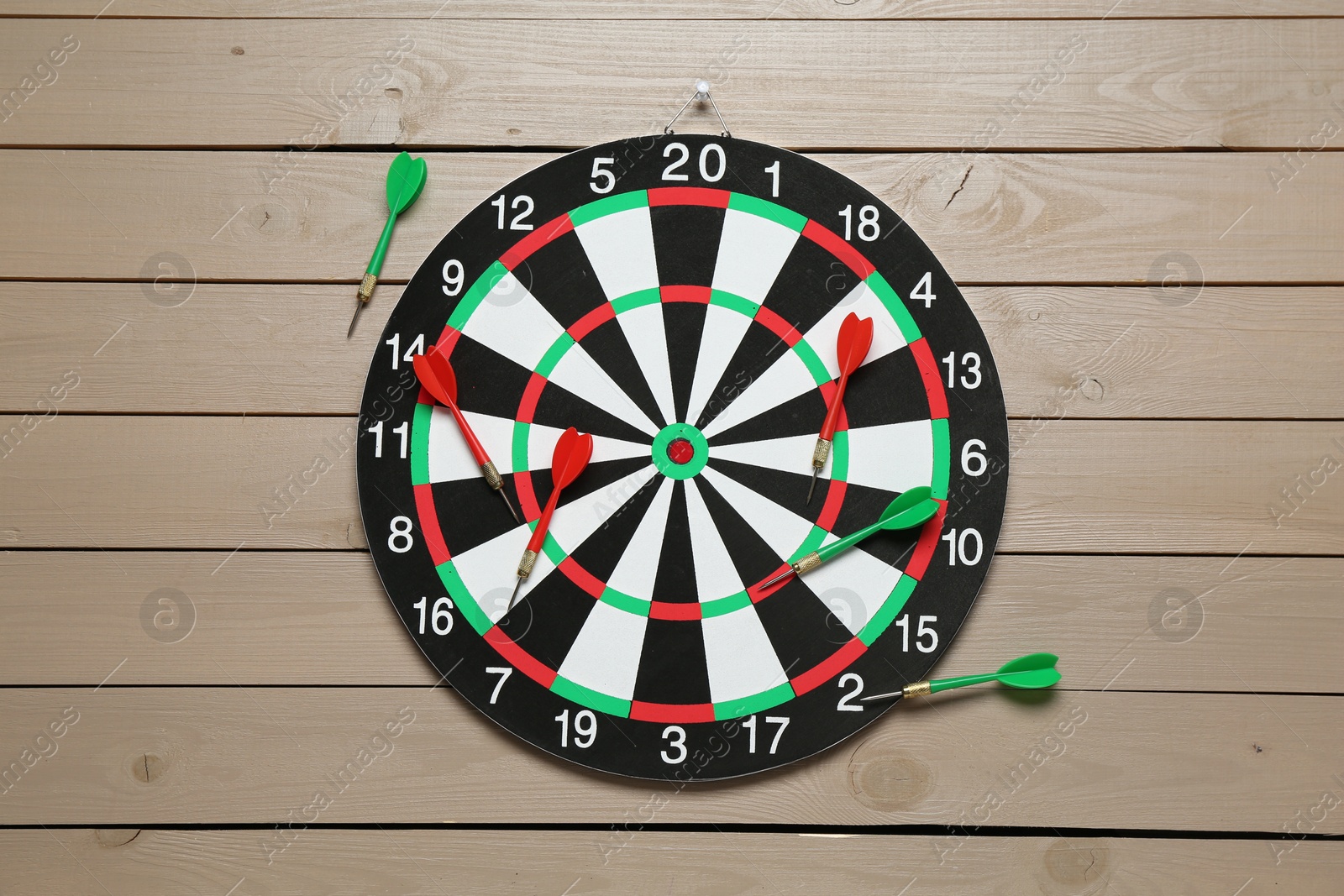 Photo of Dart board and colorful arrows on wooden background, flat lay