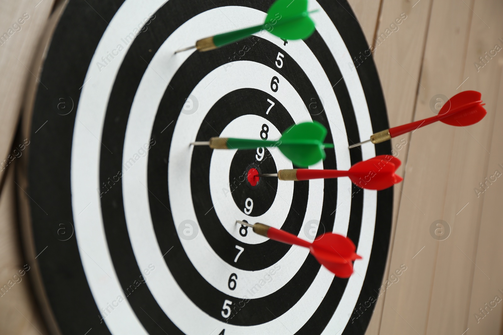 Photo of Dart board with colorful arrows on wooden background, closeup