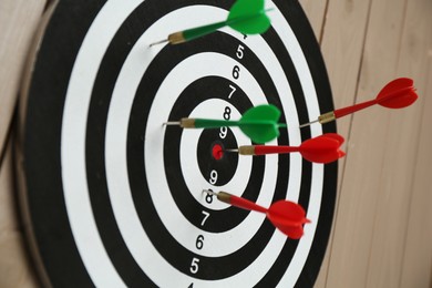 Photo of Dart board with colorful arrows on wooden background, closeup