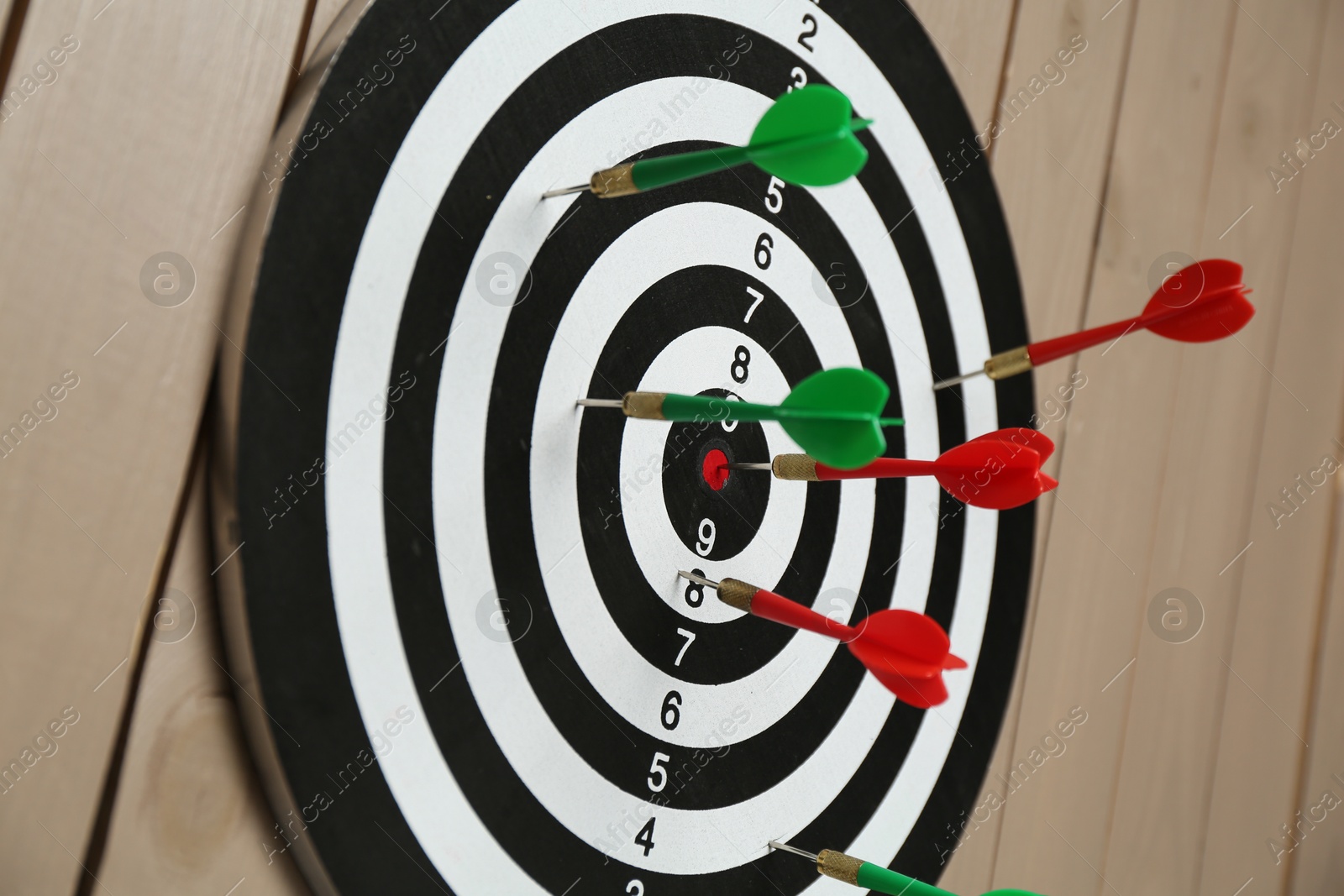 Photo of Dart board with colorful arrows on wooden background, closeup