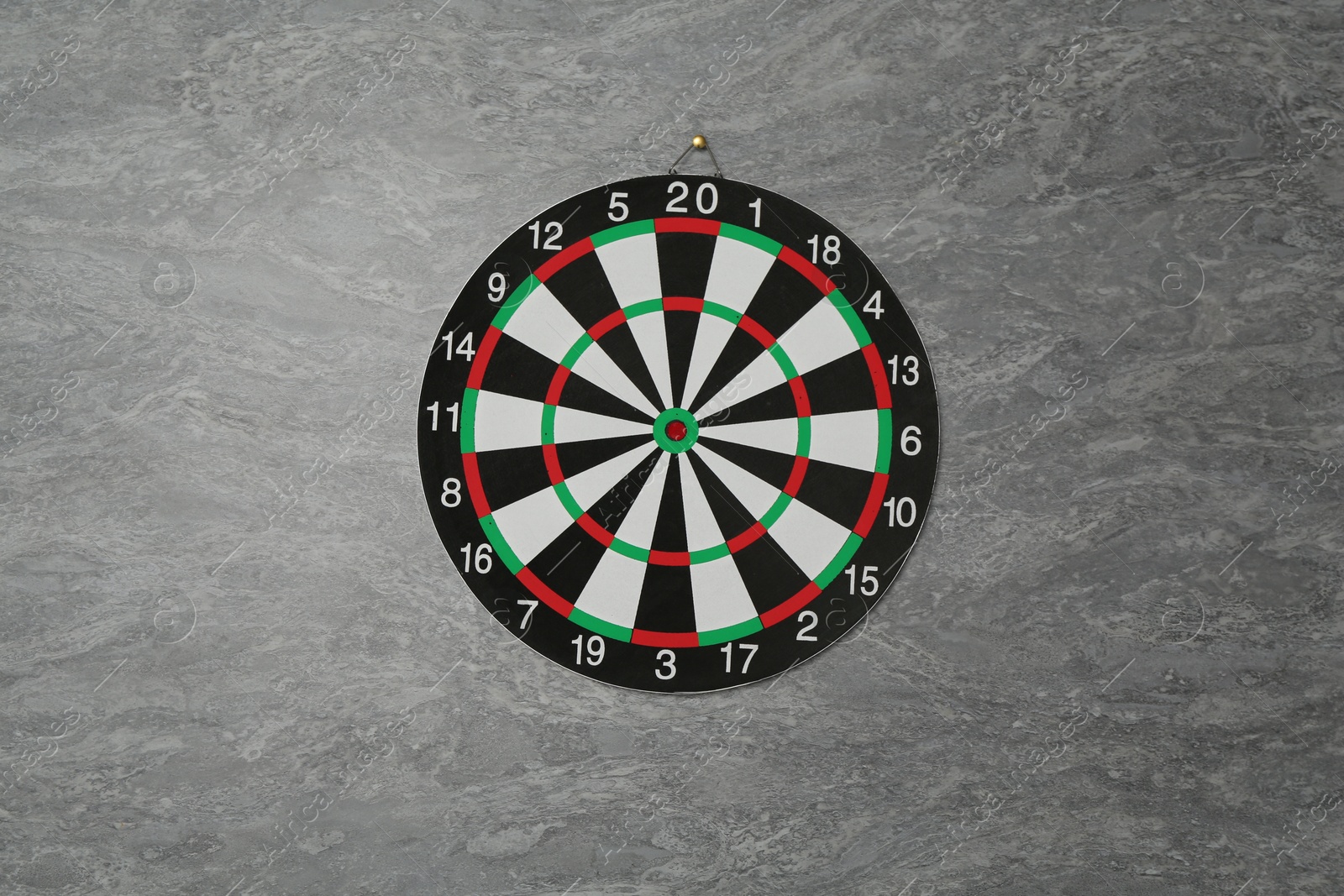 Photo of One dart board hanging on grey marble wall