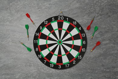 Photo of Dart board and colorful arrows on grey marble background, flat lay