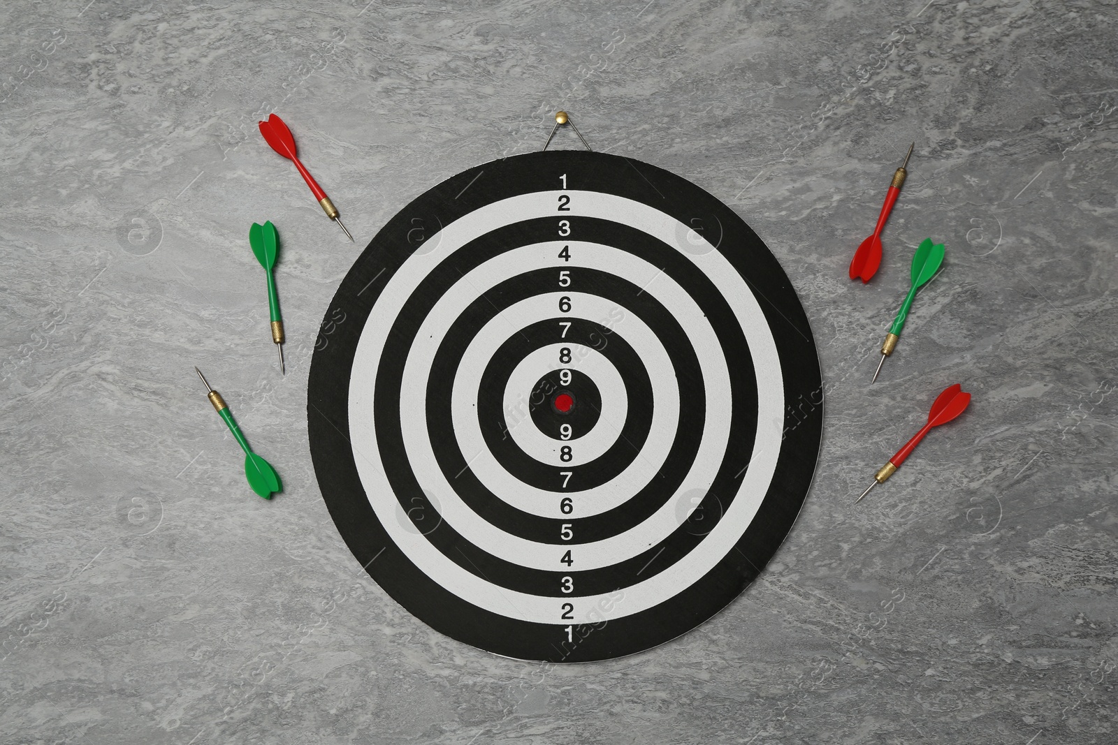 Photo of Dart board and colorful arrows on grey marble background, flat lay