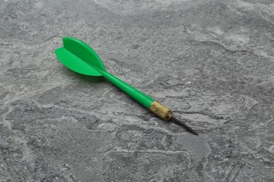 Photo of One green dart arrow on grey textured table, top view