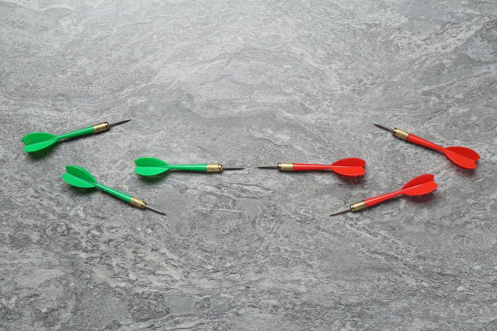 Photo of Colorful dart arrows on grey textured table, flat lay