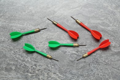 Photo of Colorful dart arrows on grey textured table, flat lay