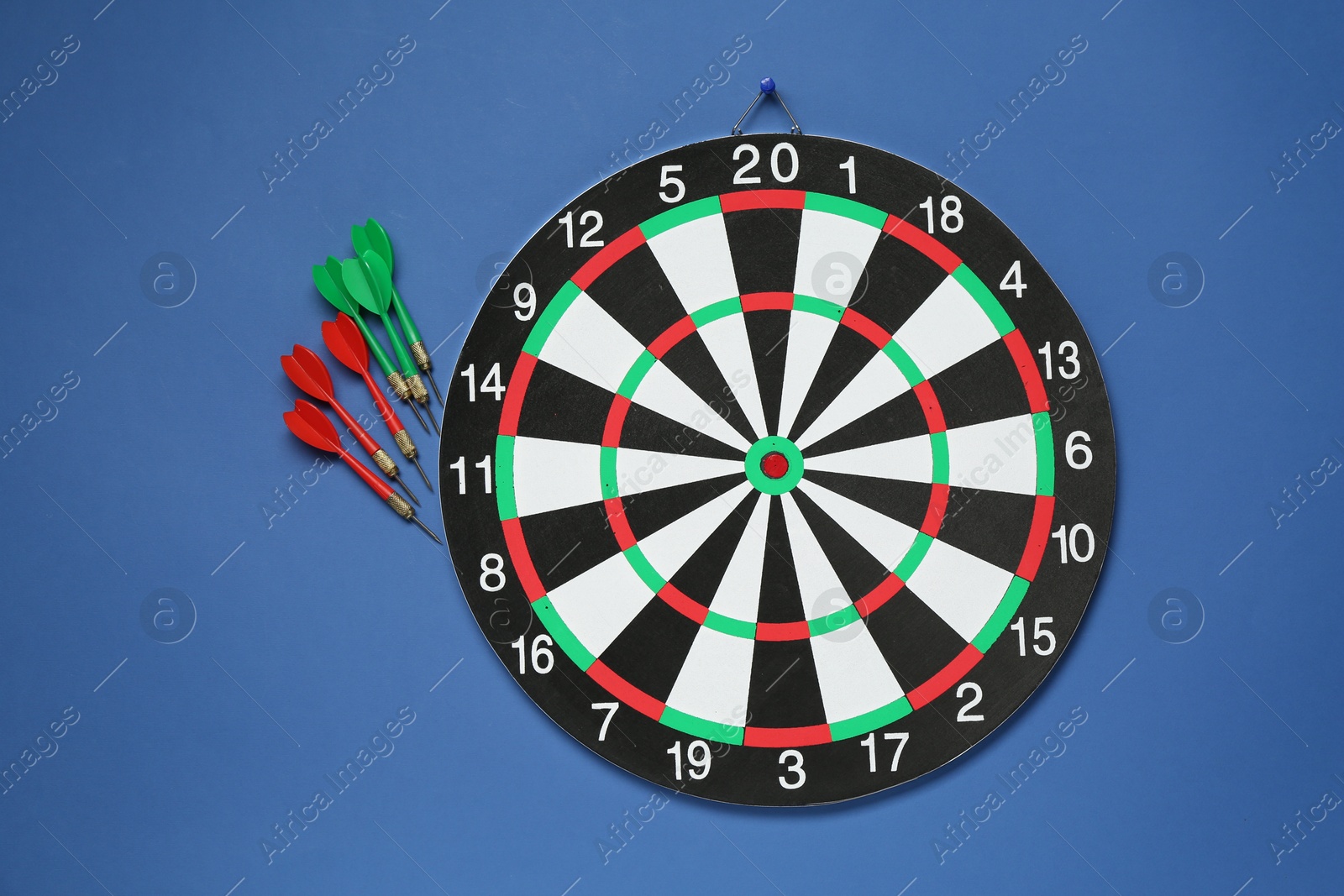 Photo of Dart board and colorful arrows on blue background, flat lay