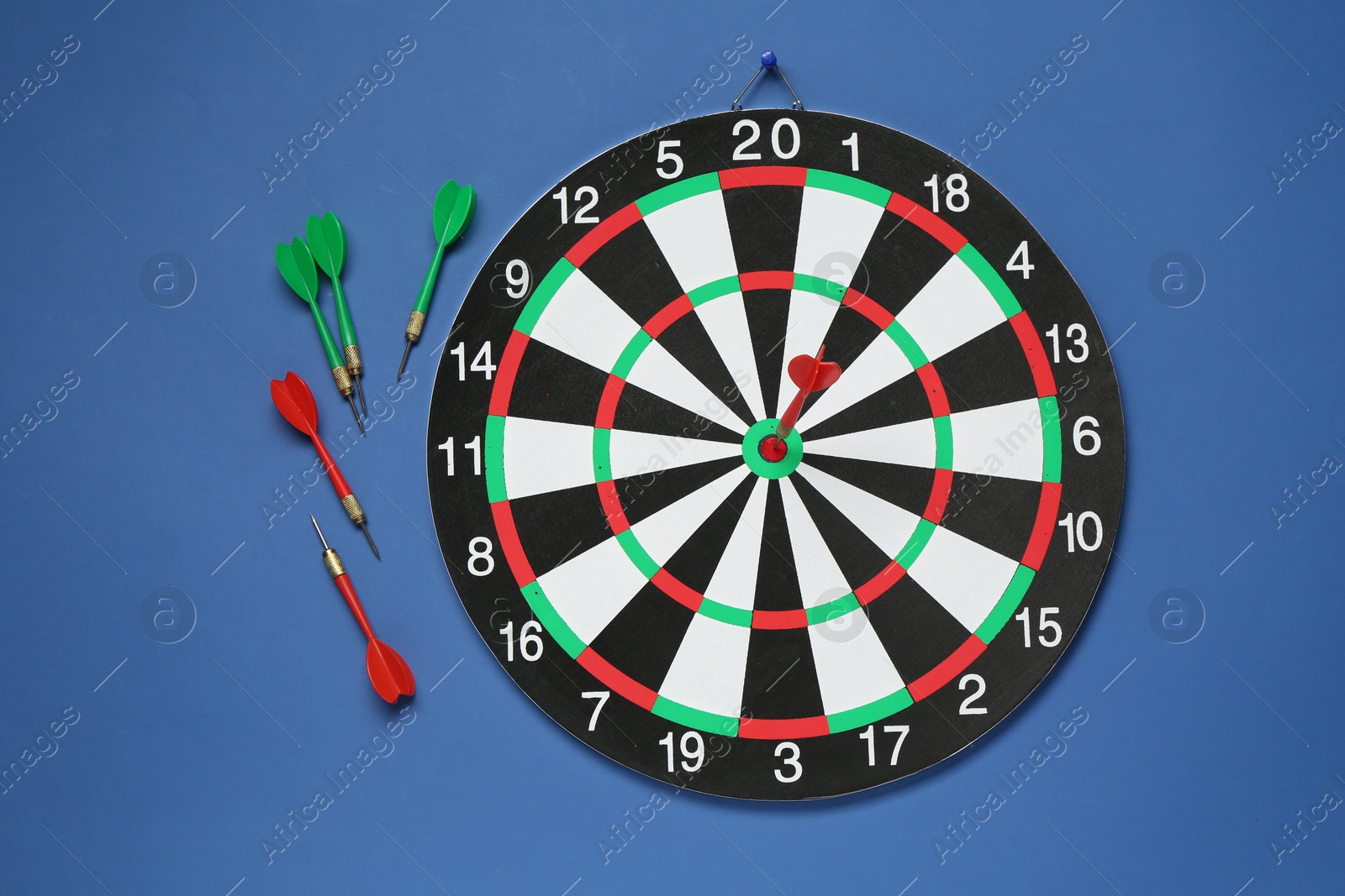 Photo of Dart board and colorful arrows on blue background, flat lay