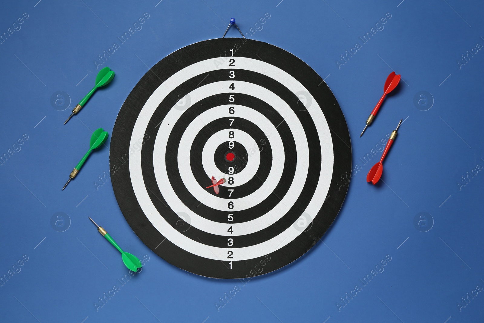 Photo of Dart board and colorful arrows on blue background, flat lay