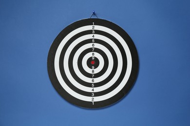 Photo of One dart board hanging on blue wall