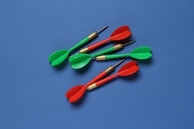 Photo of Colorful dart arrows on blue background, flat lay